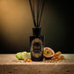HURRICANE Quiet Amber reed diffuser: a black bottle with a gold oval label, black reeds and its notes around it.