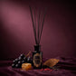 HURRICANE Velvet Nectar reed diffuser: a black bottle with a gold oval label, black reeds and its notes around it.